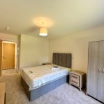 Modern bedroom with bed, wardrobe, and bedside tables.