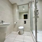 Modern bathroom with shower, toilet, and sink.