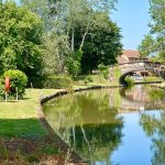 Serene canal scene with boat and bridge.