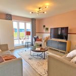 Modern living room with stylish décor and large TV.