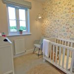 Nursery room with cot and alphabet wallpaper.