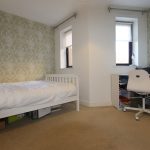 Minimalist bedroom with desk and patterned wallpaper.