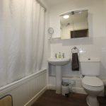 Modern bathroom with white tiles and fixtures.