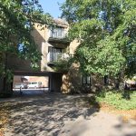 Apartment building surrounded by trees and parked cars.
