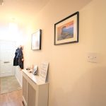 Bright hallway with coat rack and framed pictures.