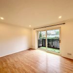 Empty room with wooden floor and patio doors.