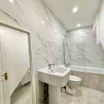 Modern bathroom with marble tiles and fixtures.