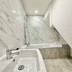 Modern bathroom with marble tiles and fixtures.