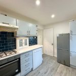 Modern kitchen with blue tiled backsplash and appliances.