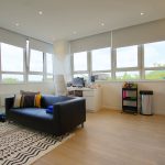 Modern open-plan room with sofa and large windows.