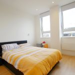Bright bedroom with double bed and large windows.