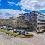 Modern office building with cars parked outside.