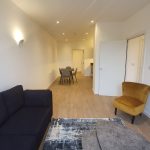 Spacious modern living room with dining area and chairs.