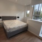 Modern bedroom with double bed and large windows.