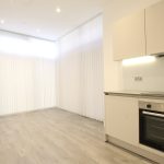 Modern kitchen with white cabinets and wooden flooring.