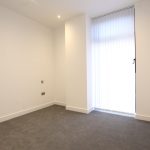 Empty room with carpet and tall window blinds.