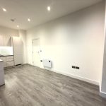 Modern kitchen with wooden flooring and white cabinets.