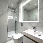Modern bathroom with marble tiles and glass shower.