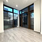 Empty room with large window and wooden floor.