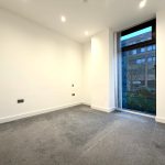 Empty room with large window, grey carpet.
