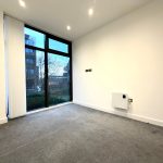 Empty room with large window and grey carpet.