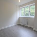 Small empty room with large window and wooden floor.