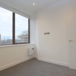 Empty room with large window and white walls.