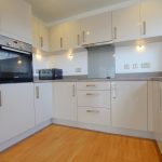Modern kitchen with white cabinets and wooden floor.