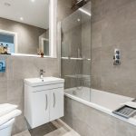 Modern bathroom with grey tiles and white fixtures.