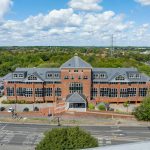 Aerial view of large brick building and parking area.