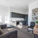 Modern living room with kitchen and artwork.