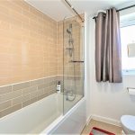 Modern bathroom with beige tiles and bathtub