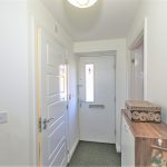 Bright hallway with white door and wooden furniture.