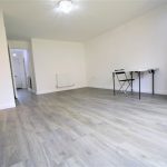 Modern, empty room with wooden flooring and desk.