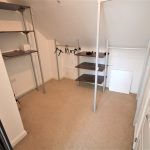 Empty walk-in wardrobe with shelves and hangers.
