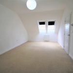 Spacious empty room with skylights and beige carpet.