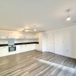 Spacious modern kitchen with wooden flooring.