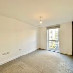 Spacious empty room with window and carpet floor.