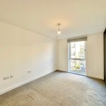 Empty room with large window and mirrored wardrobe.