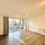 Bright empty room with wooden floor and balcony view.