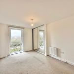 Bright empty room with large window and carpet.
