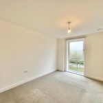 Empty room with large window and mirrored wardrobe.