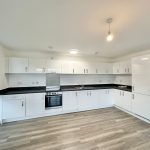 Modern white kitchen with wooden flooring.