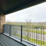 Balcony view overlooking road and trees.