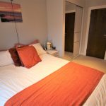Cosy bedroom with orange accents and artwork.