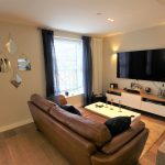 Cosy living room with large TV and sofa.