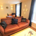Modern living room with leather sofas and wooden floor.