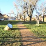 Path through park with unusual sculptures and clock.