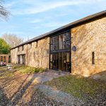 Stone barn conversion with large windows and garden.
