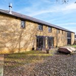 Stone house exterior with garden and patio.